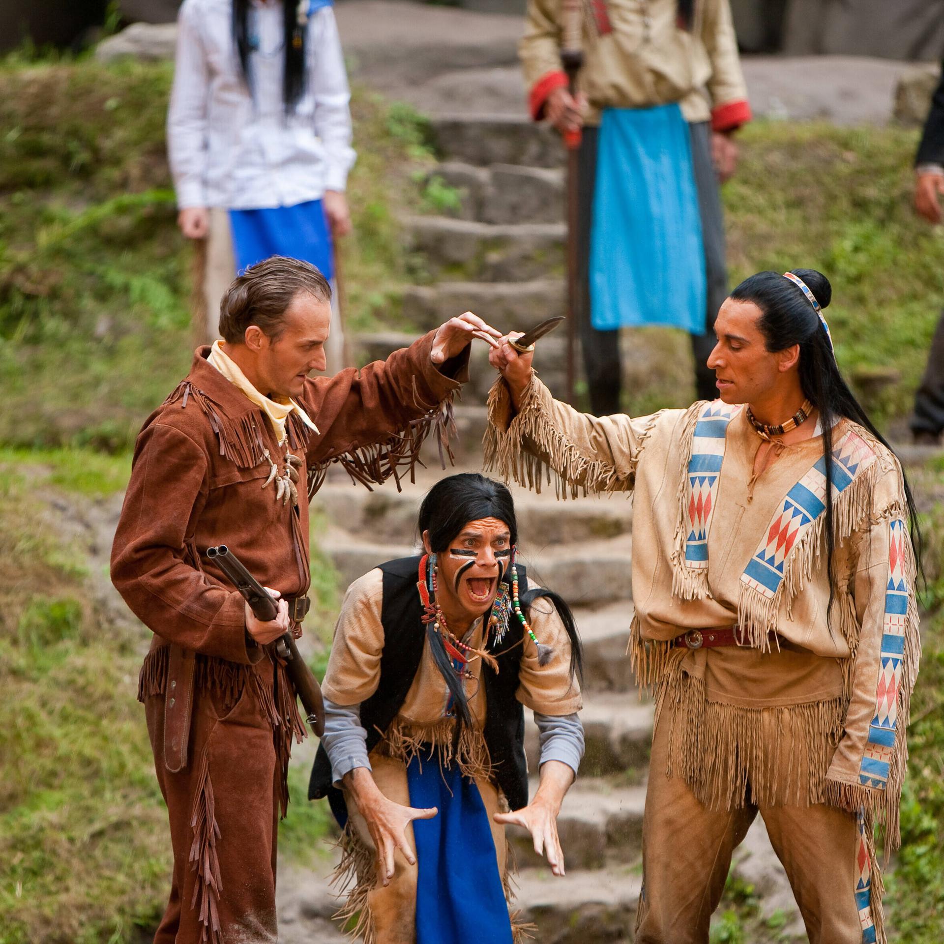 Szene aus der Karl-May-Festspiele Aufführung "Der Ölprinz". Links ein Indianer, rechts ein weisser Mann mit Gewehr.