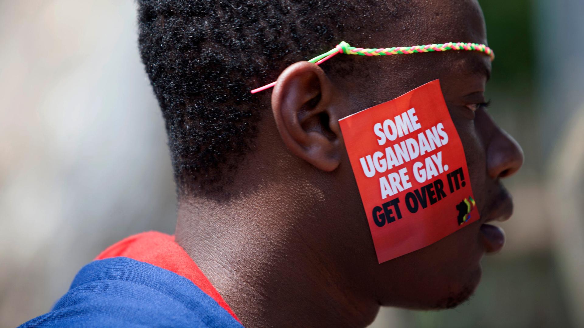 Ein Mann trägt auf seiner Wange einen Aufkleber, auf dem steht: „Some Ugandans are gay. Get over it.“ Ein Mann trägt auf seiner Wange einen Aufkleber, auf dem steht: „Some Ugandans are gay. Get over it.“