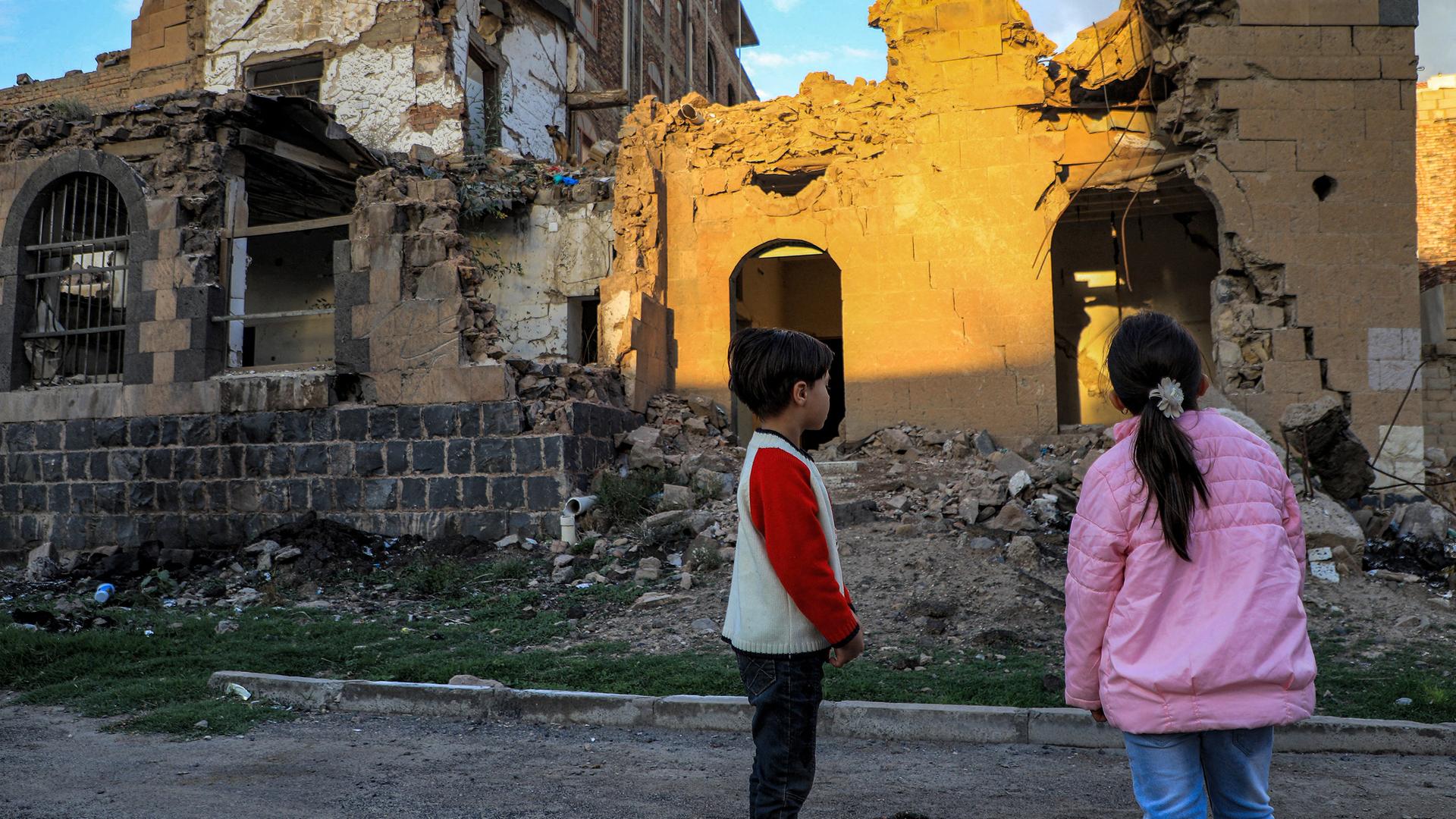 Das Foto zeigt Kinder, die vor einem zerstörten Gebäude in Sanaa, der Hauptstadt Jemens, stehen.