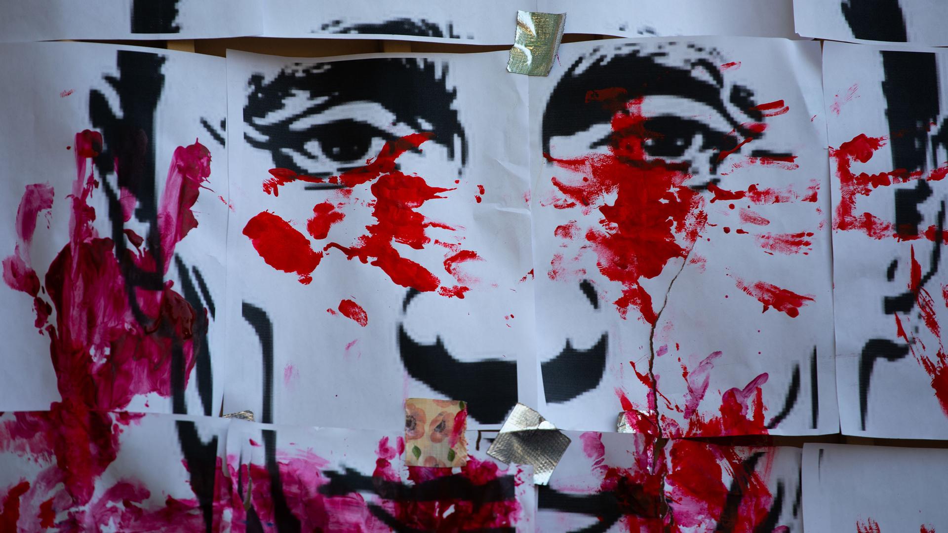 Rote Farbkleckse und Handabdrücke auf einer Zeichnung des Gesichts von Wladimir Putin. Rote Farbkleckse und Handabdrücke auf einer Zeichnung des Gesichts von Wladimir Putin.