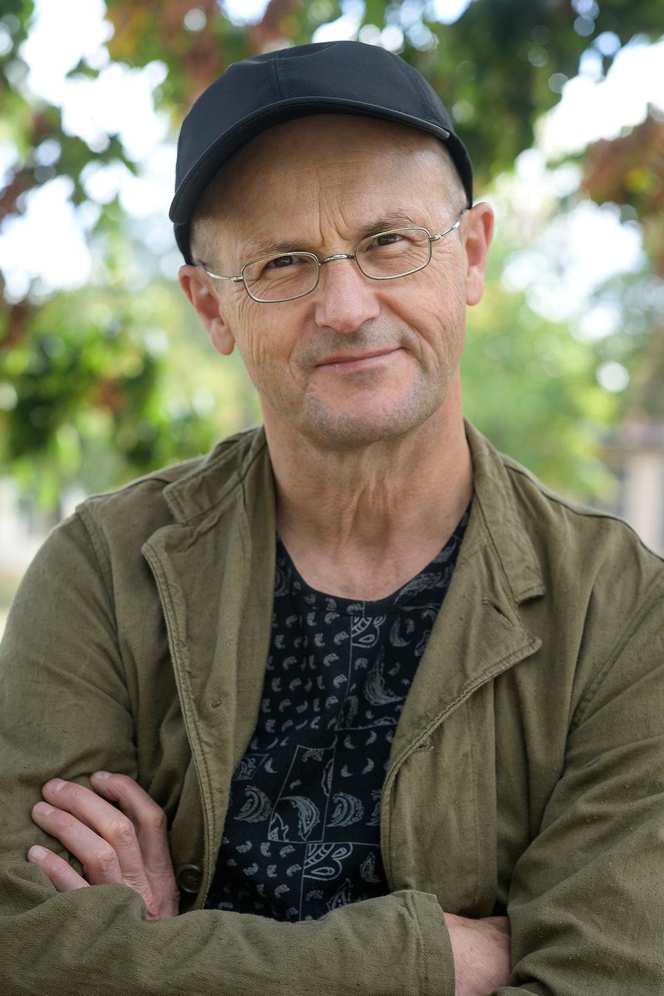 Porträt des Theaterintendanten Steffen Mensching. Er hat eine Mütze auf und lächelt freundlich in die Kamera. Porträt des Theaterintendanten Steffen Mensching. Er hat eine Mütze auf und lächelt freundlich in die Kamera.