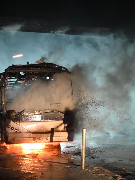 Feuerwehrmänner löschen an der Sonnenallee einen Reisebus, der von Unbekannten angezündet worden war.