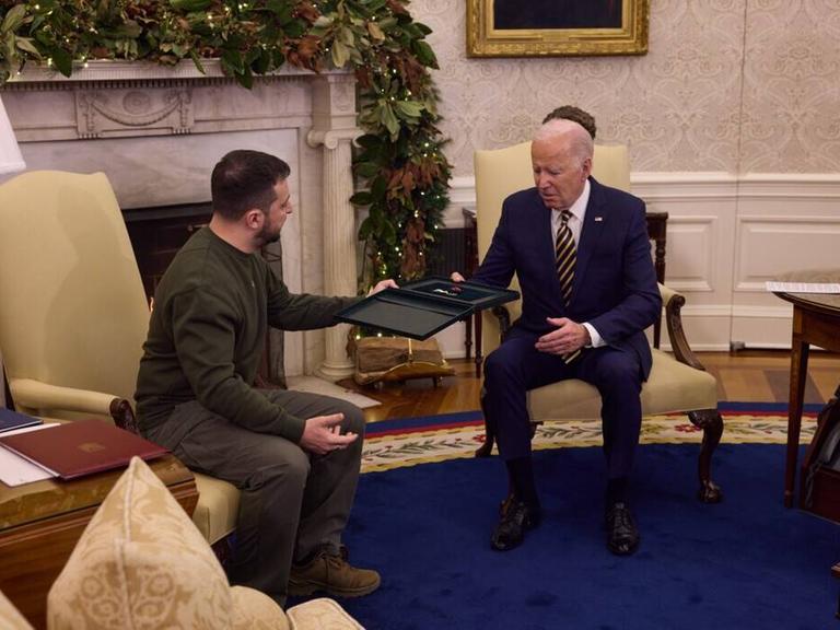 Der ukrainische Präsident Selenskyj übergibt US-Präsident Biden vor einem Kamin im Weißen Haus in Washington einen Orden.