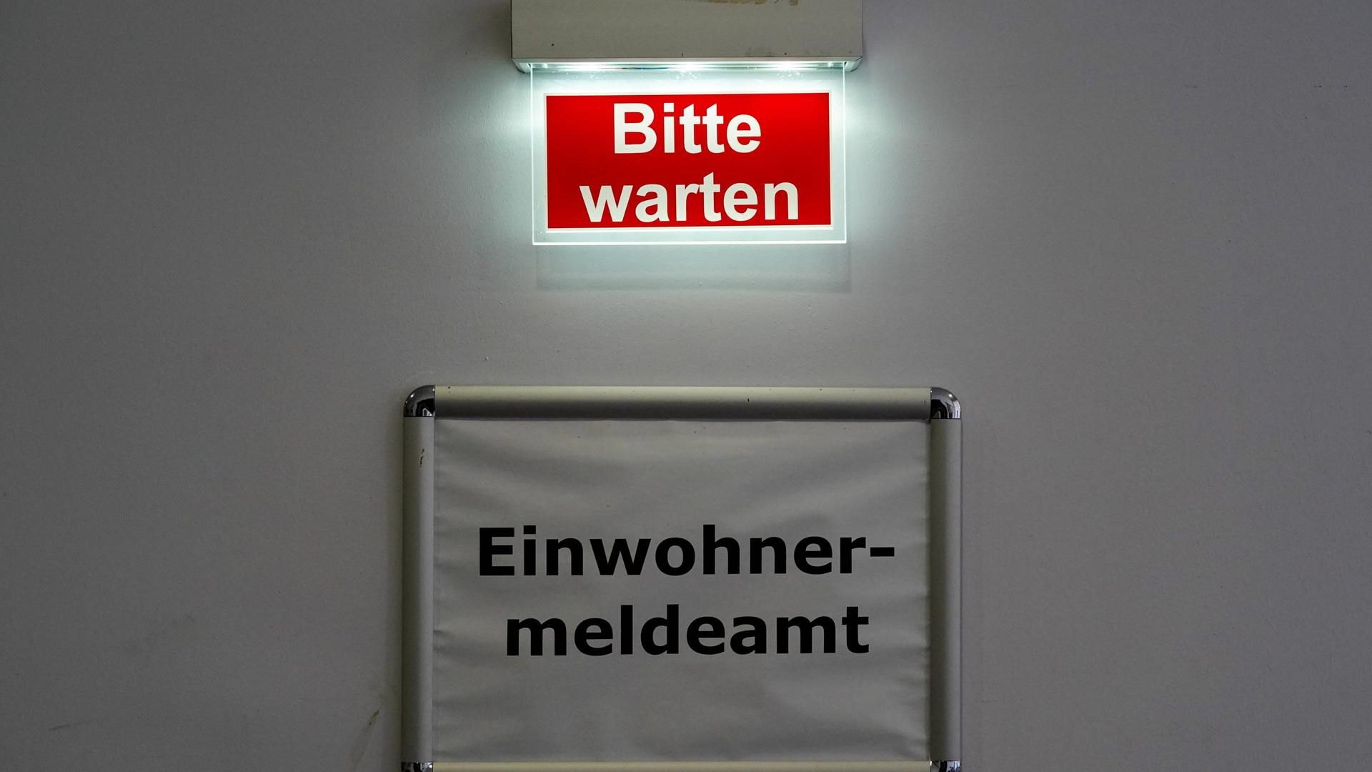 Der Schriftzug Bitte warten steht über dem Schild des Behördenbereichs Einwohnermeldeamt. Markkleeberg, Sachsen, Deutschland Der Schriftzug Bitte warten steht über dem Schild des Behördenbereichs Einwohnermeldeamt. Markkleeberg, Sachsen, Deutschland