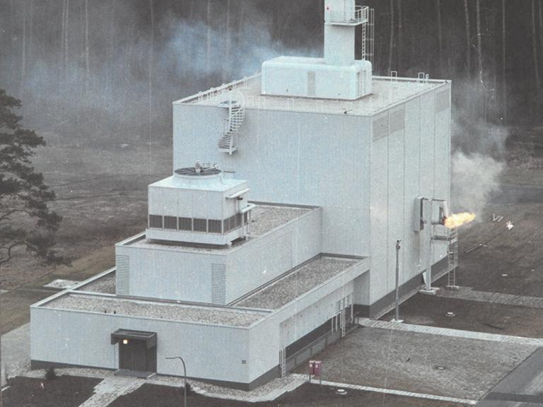 Abbildung eines Kernforschungszentrums, aus dessen Seite Feuer austritt.