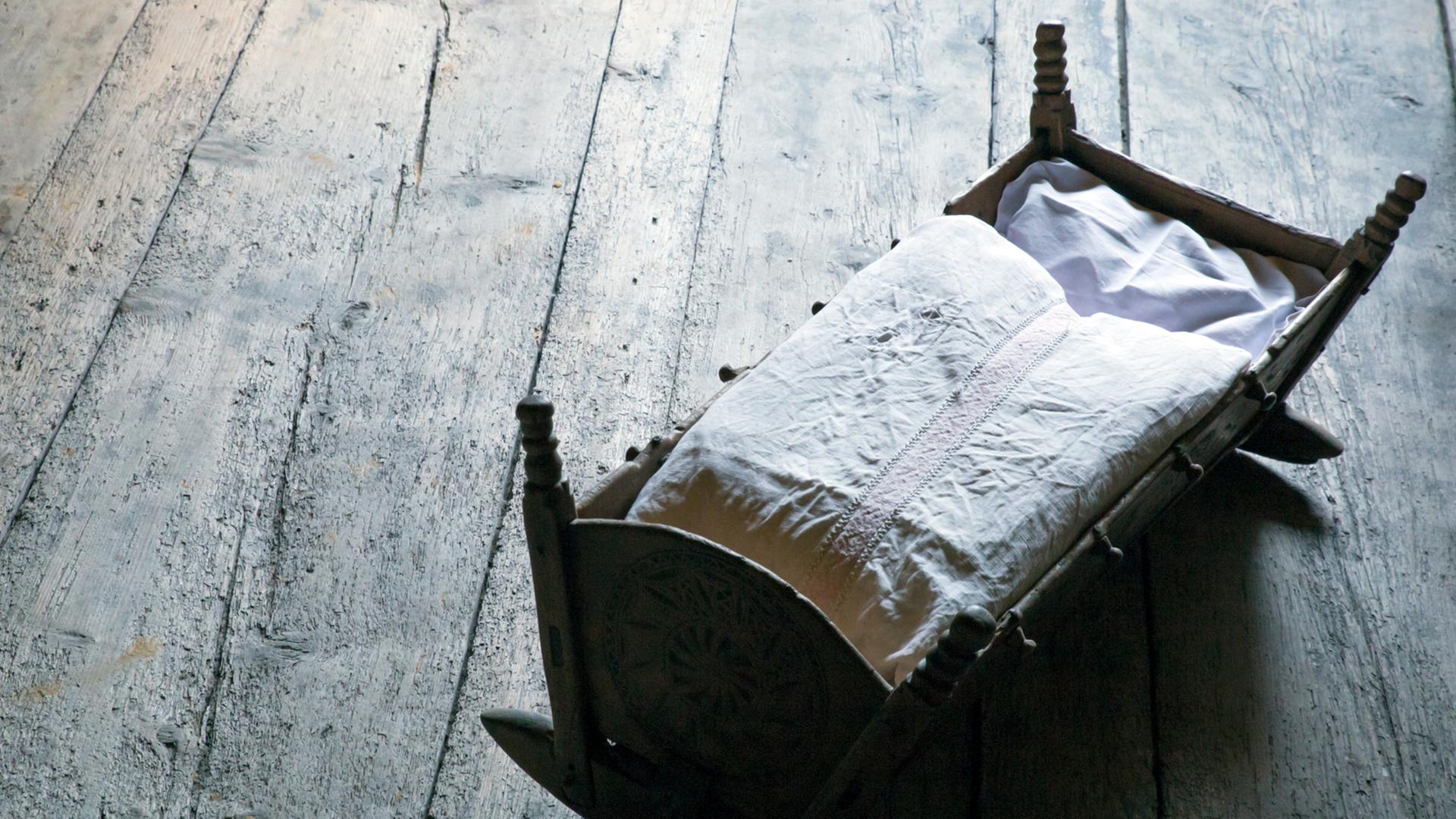 Annegret Krauser hat vor ihrem Tod entbunden. Wo ist das Kind? Zu sehen: Ein Kinderbett auf einem grauen Holzboden. Annegret Krauser hat vor ihrem Tod entbunden. Wo ist das Kind? Zu sehen: Ein Kinderbett auf einem grauen Holzboden.