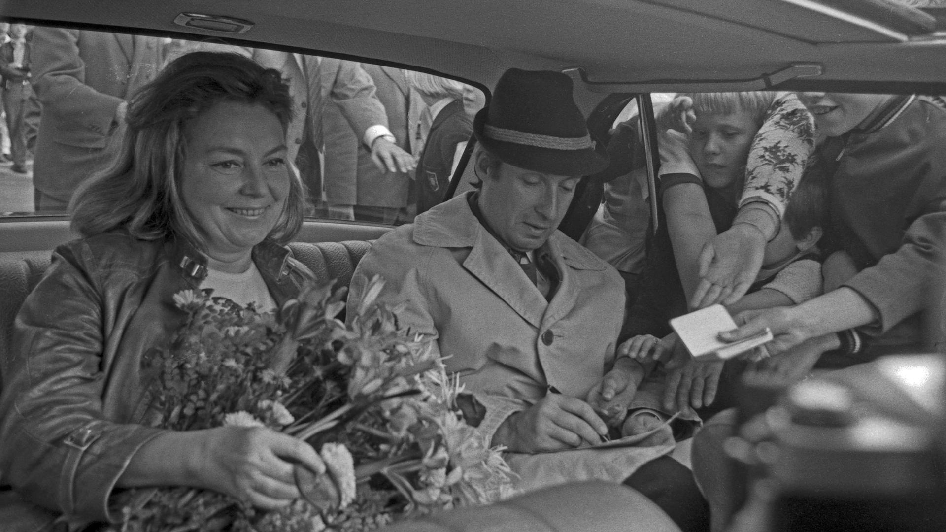 Schwarzweißbild von Peter Alexander und Hilde Haagen, die nebeneinander im Auto sitzen. Durch das Fenster stecken Fans Zettel mit Autogrammwünschen hinein. Schwarzweißbild von Peter Alexander und Hilde Haagen, die nebeneinander im Auto sitzen. Durch das Fenster stecken Fans Zettel mit Autogrammwünschen hinein.