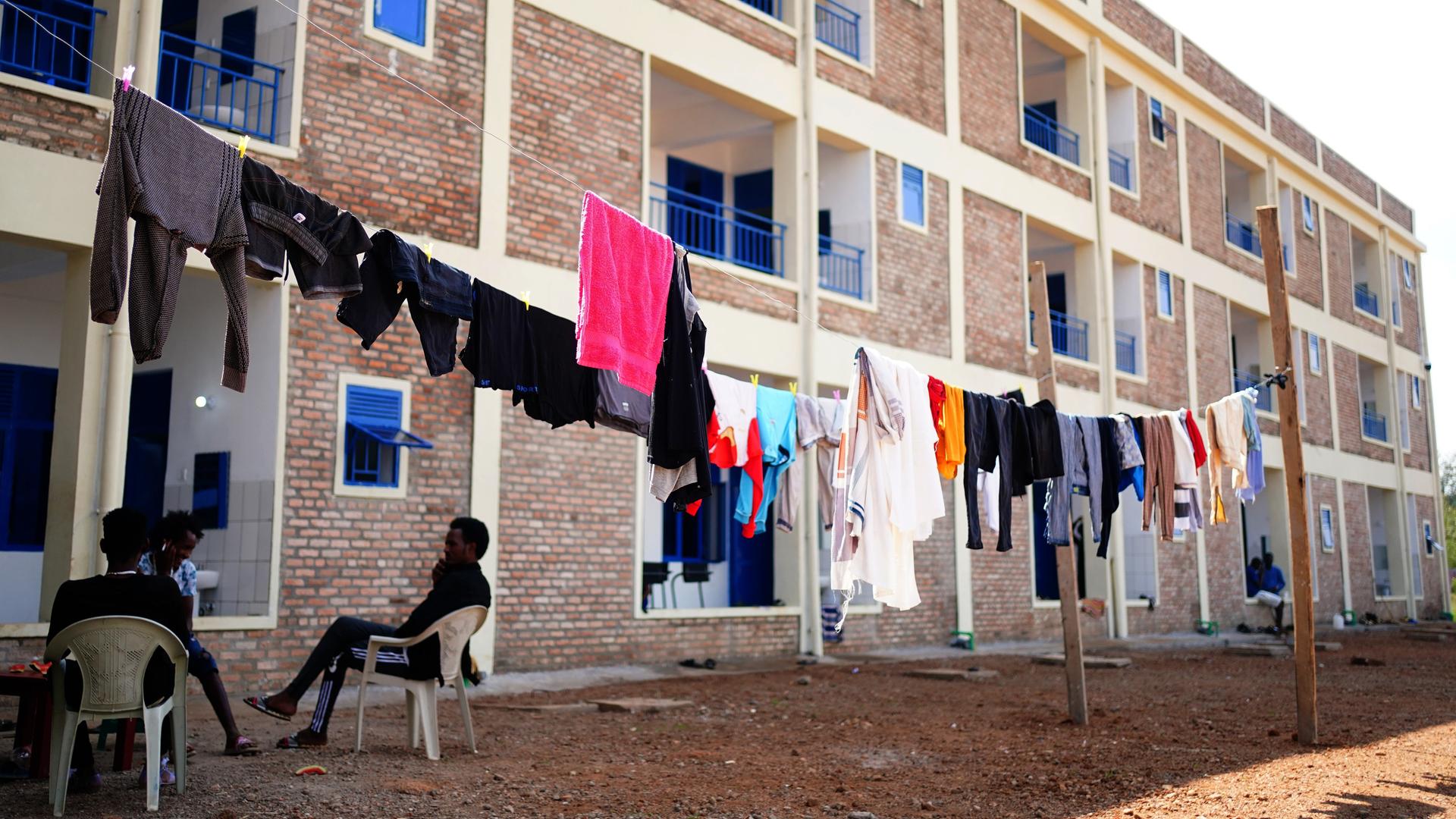 Ein Wohnblock, davor hängt Wäsche, einige Menschen sitzen auf Plastikstühlen: die Unterkünften im Flüchtlingscamp Gashora in Ruanda.