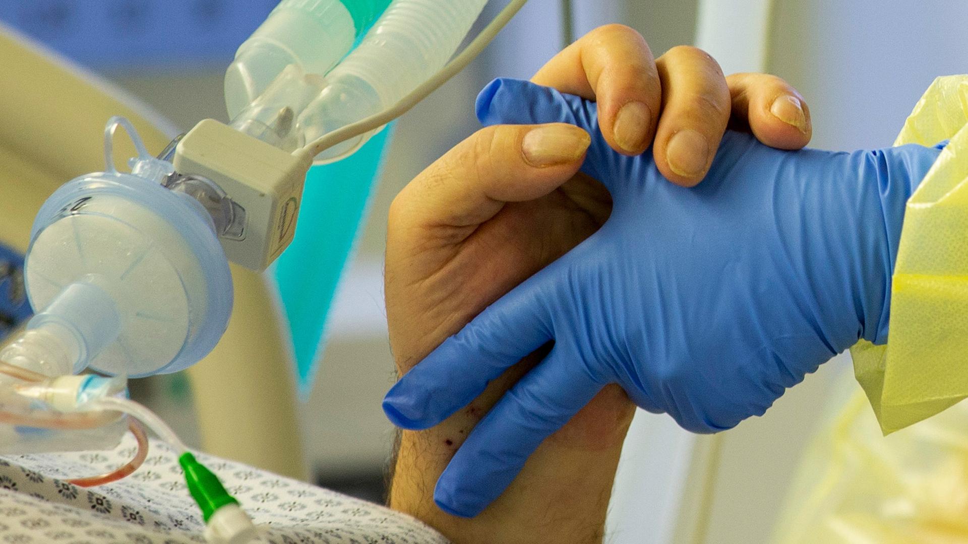 Eine Krankenschwester hält die Hand eines Covid-Patienten auf der Intensivstation des Krankenhauses Düren. 