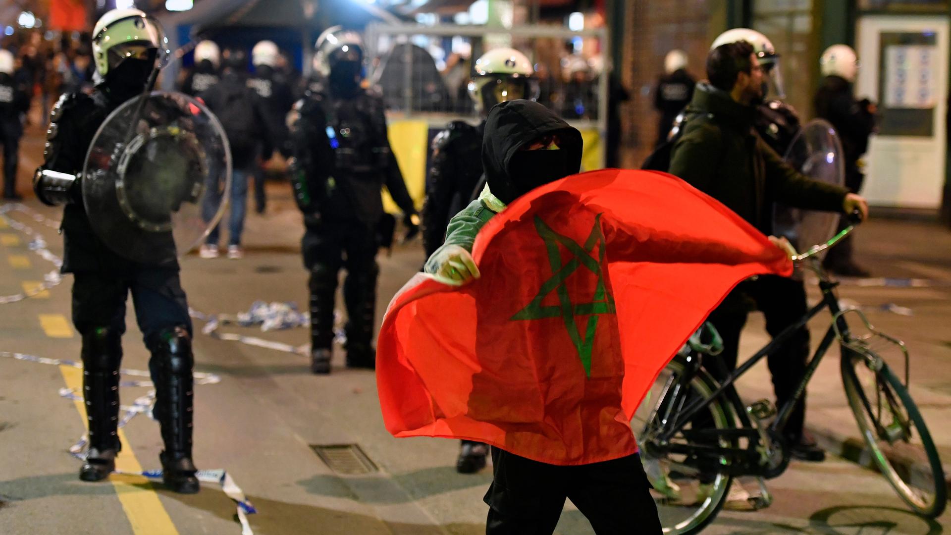 Polizisten und marokkanische Fans stehen auf einer Straße in Brüssel. Polizisten und marokkanische Fans stehen auf einer Straße in Brüssel.