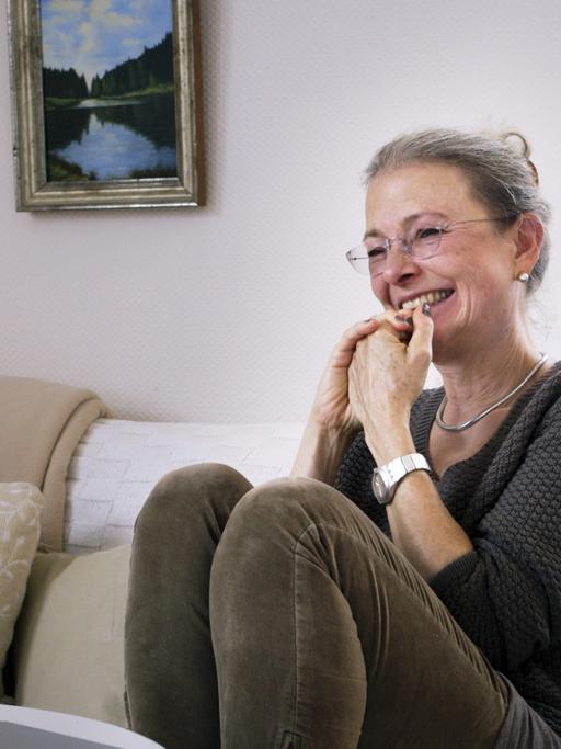 Filmstill aus der Doku: "ER SIE ICH" von Carlotta Kittel. Die Mutter sitzt auf einem Sofa und lacht.