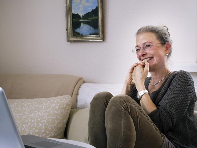Filmstill aus der Doku: "ER SIE ICH" von Carlotta Kittel. Die Mutter sitzt auf einem Sofa und lacht.