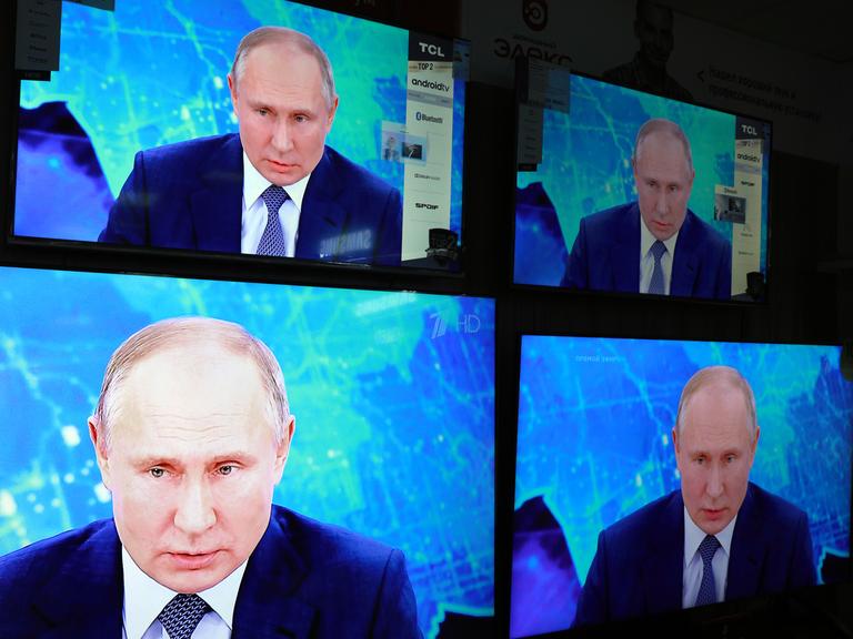 Das Gesicht Vladimir Putins vierfach auf einem Bildschirm.