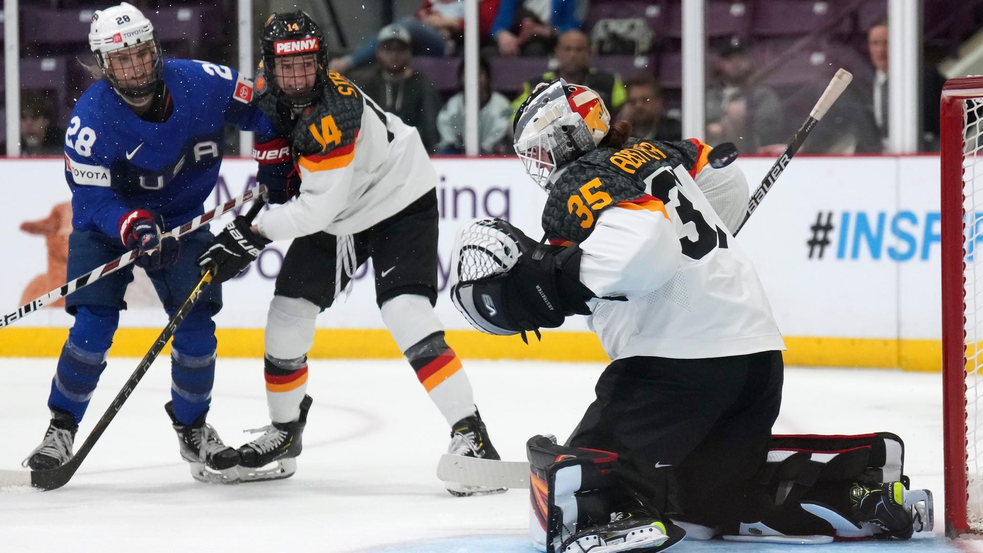 Amanda Kessel aus den USA gegen Carina Strobel und Tor-Hüterin Sandra Abstreiter aus Deutschland. Amanda Kessel aus den USA gegen Carina Strobel und Tor-Hüterin Sandra Abstreiter aus Deutschland.