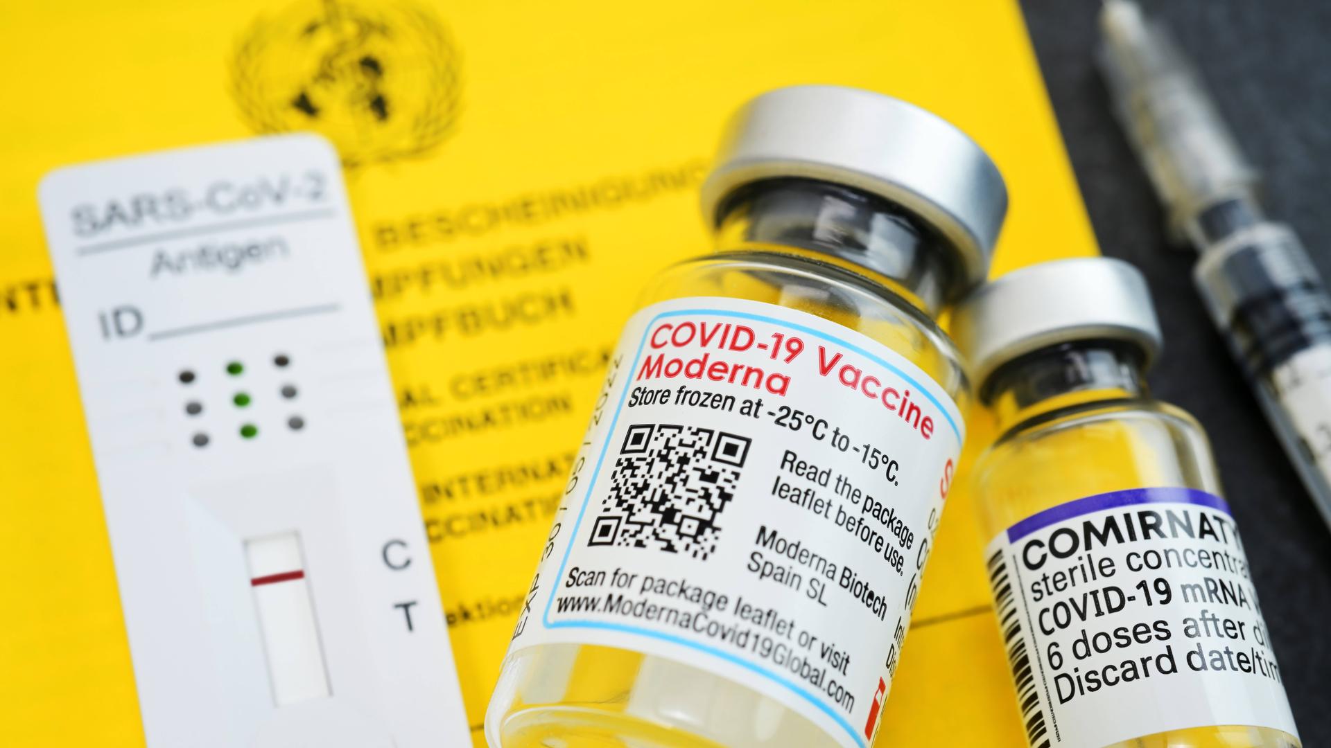 Impfausweis mit Impfspritze, negativem Corona-Schnelltest und Impfstofffläschchen von Biontech und Moderna Impfausweis mit Impfspritze, negativem Corona-Schnelltest und Impfstofffläschchen von Biontech und Moderna