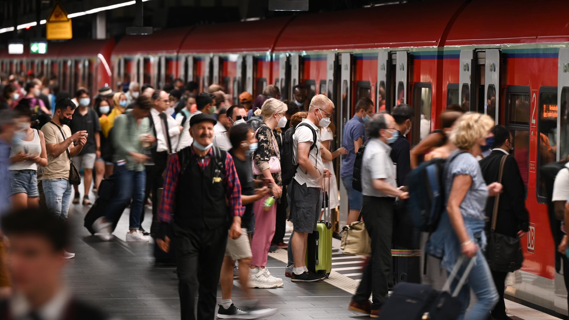Zugreisende auf einem vollen Bahngleis, einige steigen in eine S-Bahn ein. Zugreisende auf einem vollen Bahngleis, einige steigen in eine S-Bahn ein.