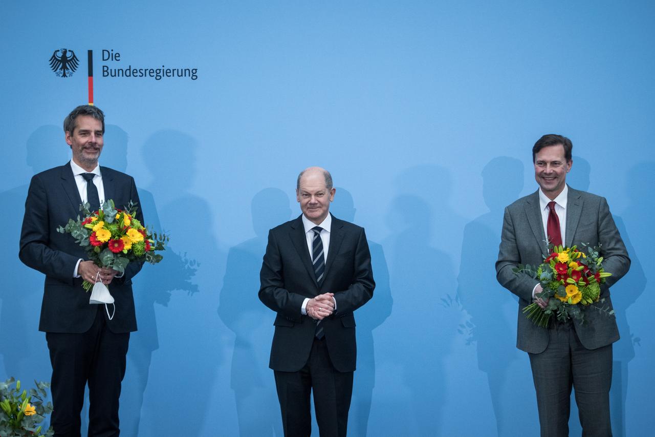 Steffen Hebestreit (l.) steht bei der Amtsübergabe neben seinem Vorgänger Steffen Seibert (r.) und Kanzler Olaf Scholz (SPD)