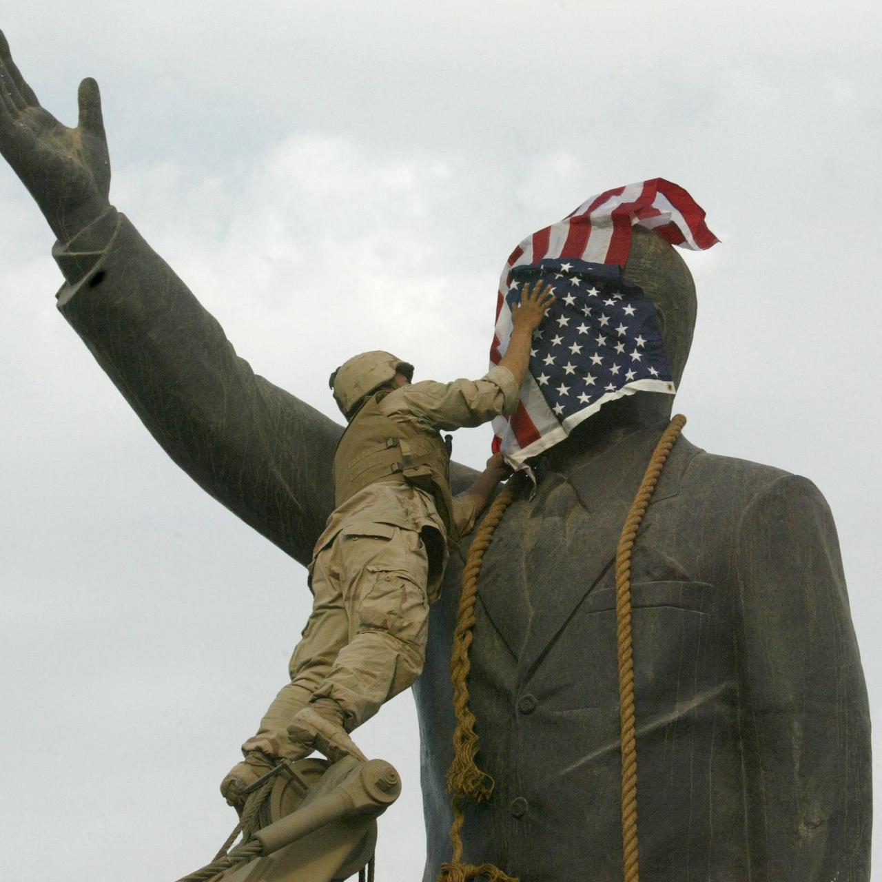 Das Foto zeigt einen US-Soldaten, der am 9. April 2003 das Gesicht der Statue des irakischen Präsidenten Saddam Hussein mit der US-Flagge auf dem al-Fardous-Platz in Bagdad bedeckt. Das Foto zeigt einen US-Soldaten, der am 9. April 2003 das Gesicht der Statue des irakischen Präsidenten Saddam Hussein mit der US-Flagge auf dem al-Fardous-Platz in Bagdad bedeckt.