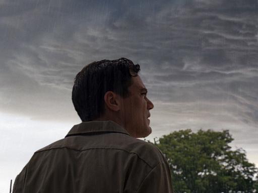 Ein Mann blickt ängstlich auf einen düsteren Gewitterhimmel.