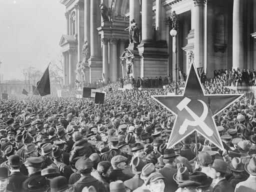 Demonstrierende vor dem Berliner Reichstag halten einen Stern mit Hammer und Sichel in die Höhe.