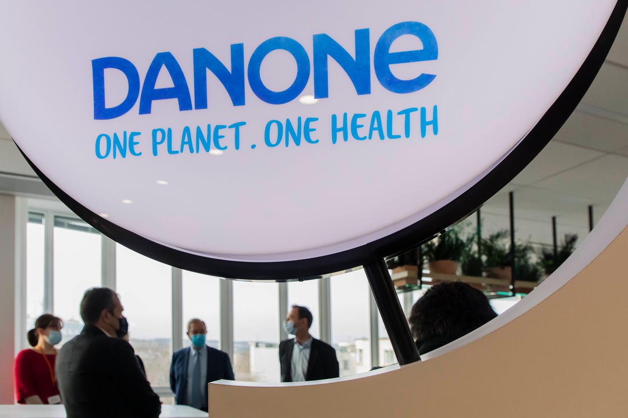 Einige Herren mit Mundschutz unterhalten sich im Schatten einer riesigen Danone-Werbe-Installation. Einige Herren mit Mundschutz unterhalten sich im Schatten einer riesigen Danone-Werbe-Installation.
