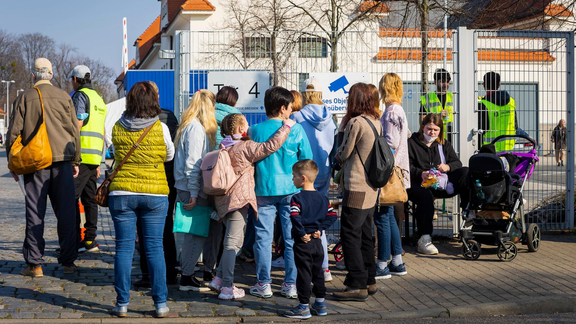 Familien mit Kindern stehen vor einem Zaun. Familien mit Kindern stehen vor einem Zaun.