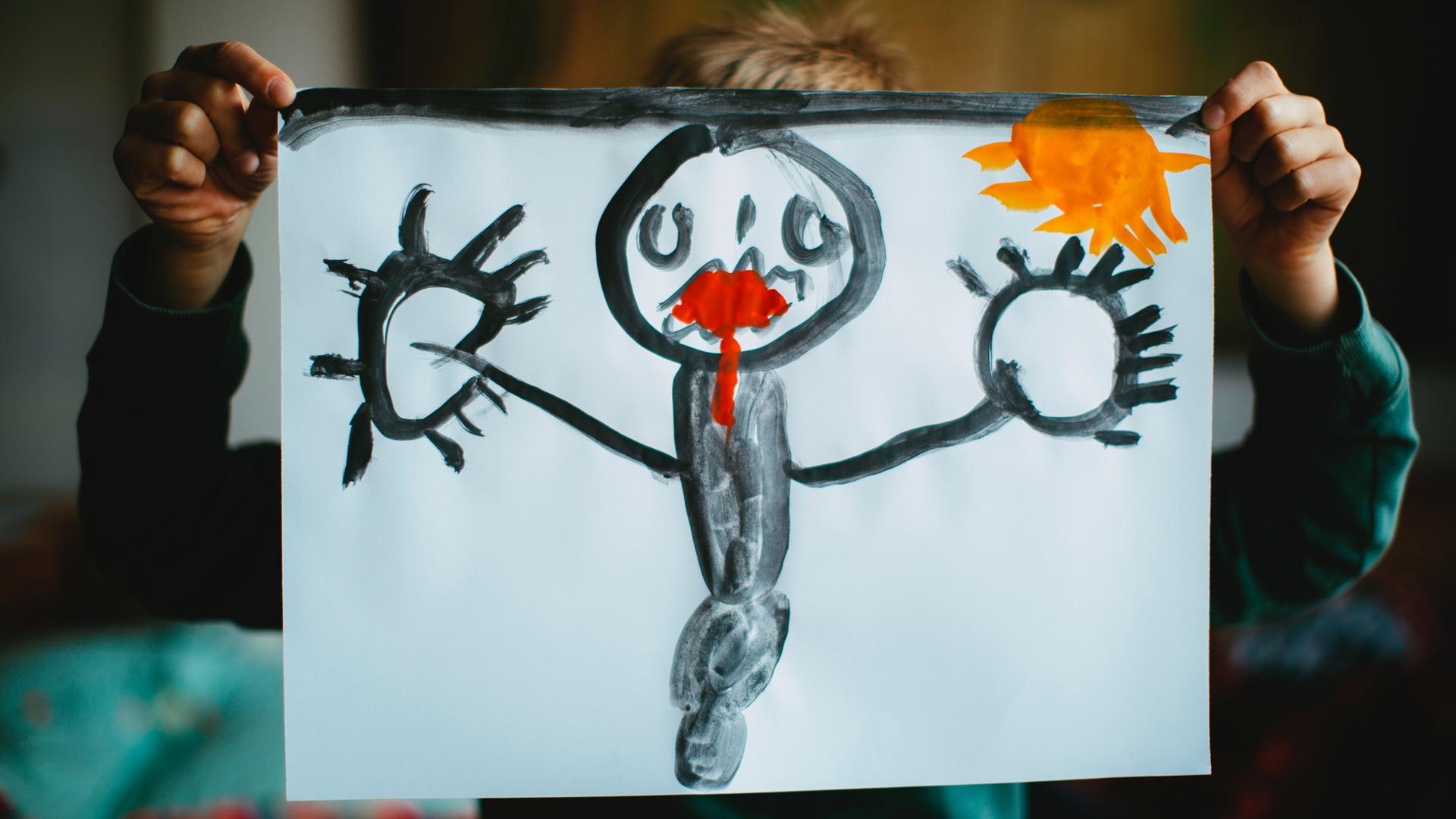 Ein Kind hält ein selbstgemaltes Bild vor seinen Kopf. Dem Mensch auf dem Bild läuft rote Farbe aus dem Mund.