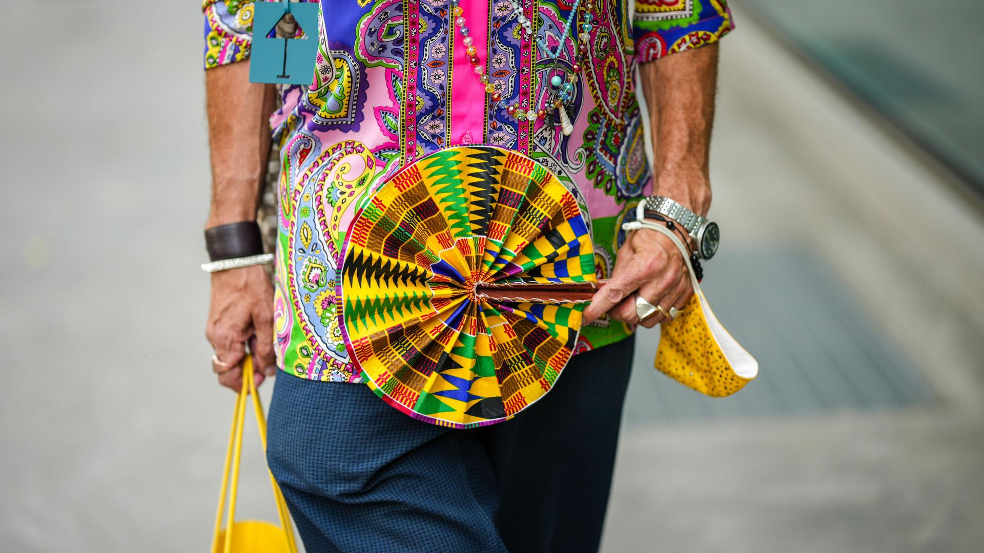 Street Style: Ein Mann mit buntem Fächer auf der Fashion Week in Mailand, 2022. Street Style: Ein Mann mit buntem Fächer auf der Fashion Week in Mailand, 2022.
