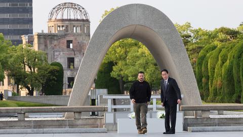 Japans Premierminister Fumio Kishida (r.) und der ukrainische Präsident Wolodymyr Selenskyj stehen vor dem Kenotaph für die Opfer der Atombombe im Friedenspark Hiroshima.