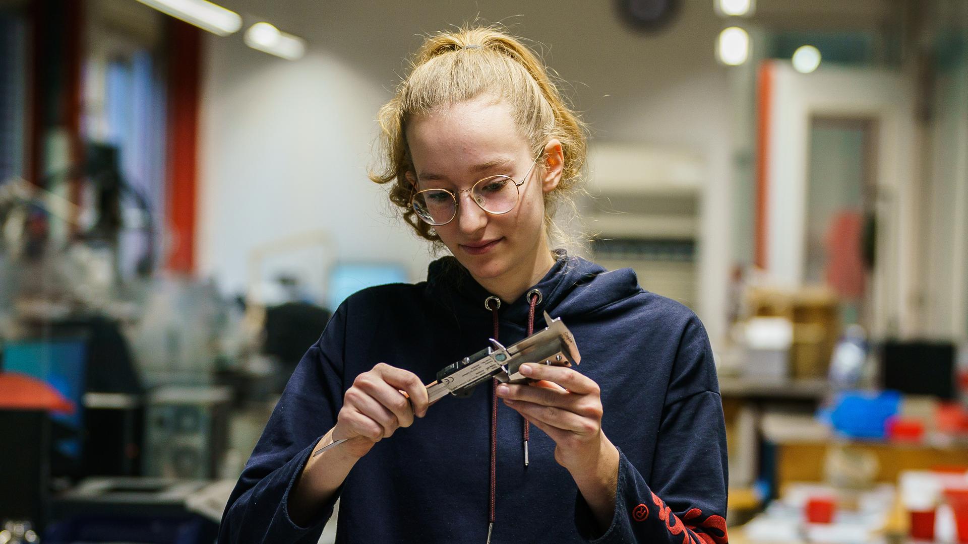 Neuntklässlerin mit einem Werkstück beim Betriebspraktikum zur Berufsorientierung Neuntklässlerin mit einem Werkstück beim Betriebspraktikum zur Berufsorientierung
