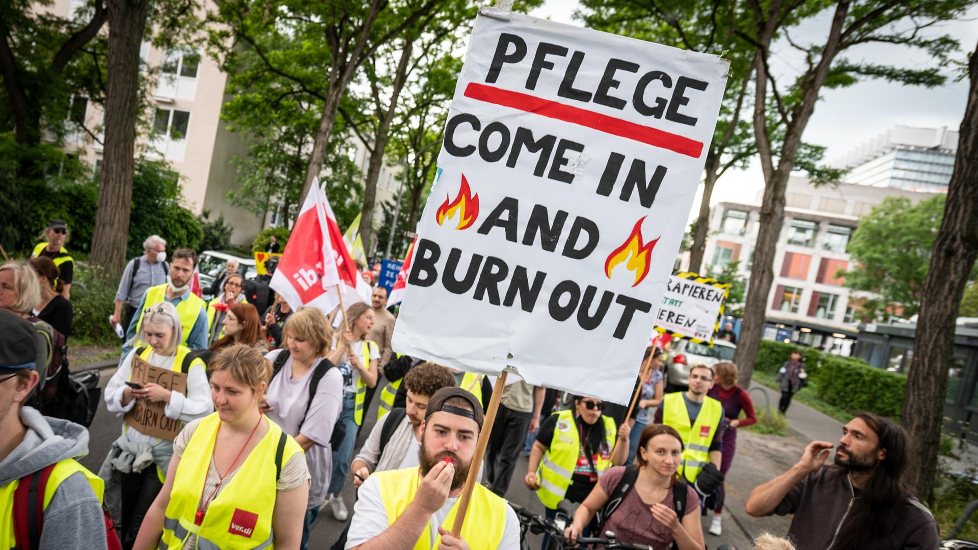 Mit einem Plakat "Pflege - come in and burn out" nehmen Pflegekräfte an einer Demonstration teil. Mit einem Plakat "Pflege - come in and burn out" nehmen Pflegekräfte an einer Demonstration teil.