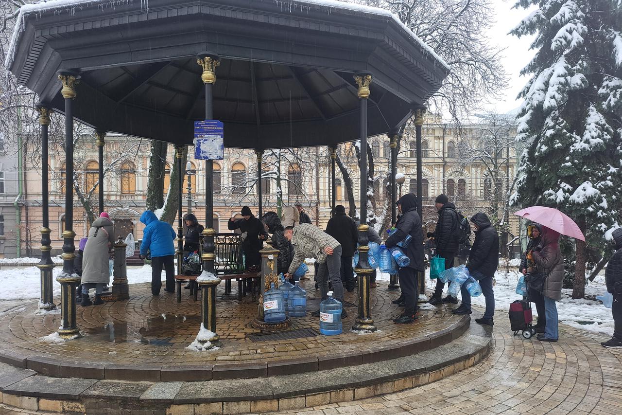 Menschen stehen Schlange vor einem öffentlichen Trinkwasser-Brunnen in Kiew. Sie haben große Kunststoff-Behälter dabei, um sie zu füllen. Menschen stehen Schlange vor einem öffentlichen Trinkwasser-Brunnen in Kiew. Sie haben große Kunststoff-Behälter dabei, um sie zu füllen.