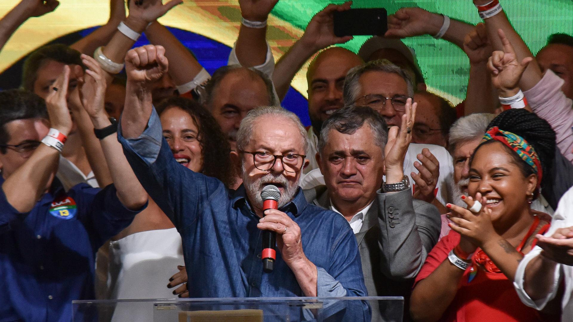Luiz Inácio Lula da Silva hält eine Rede. Er streckt die Faust in den Himmel. Um ihn herum stehen Anhänger und Anhängerinnen. Luiz Inácio Lula da Silva hält eine Rede. Er streckt die Faust in den Himmel. Um ihn herum stehen Anhänger und Anhängerinnen.