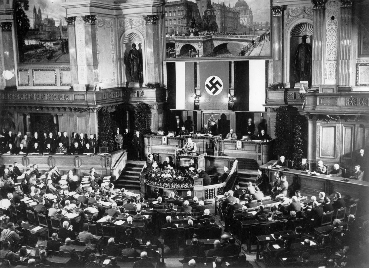 Schwarz-Weiß-Aufnahme von 1933: Hermann Göring steht am Rednerpult des Preußischen Landtags. Hinter ihm eine riesige Hakenkreuzfahne.