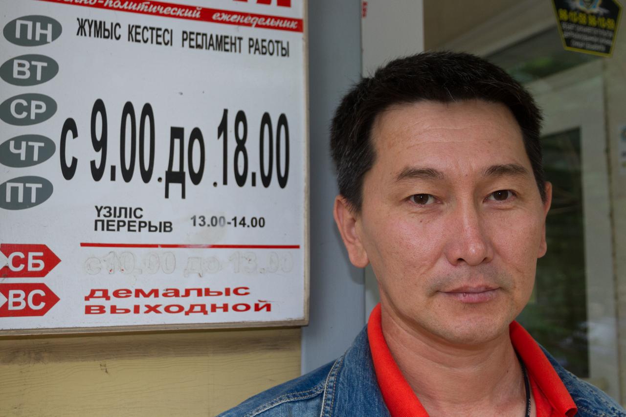 Der kasachische Journalist Lukpan Akhmedyarov hat schwarze Haare, trägt eine Jeansjacke und schaut in die Kamera. Der kasachische Journalist Lukpan Akhmedyarov hat schwarze Haare, trägt eine Jeansjacke und schaut in die Kamera.
