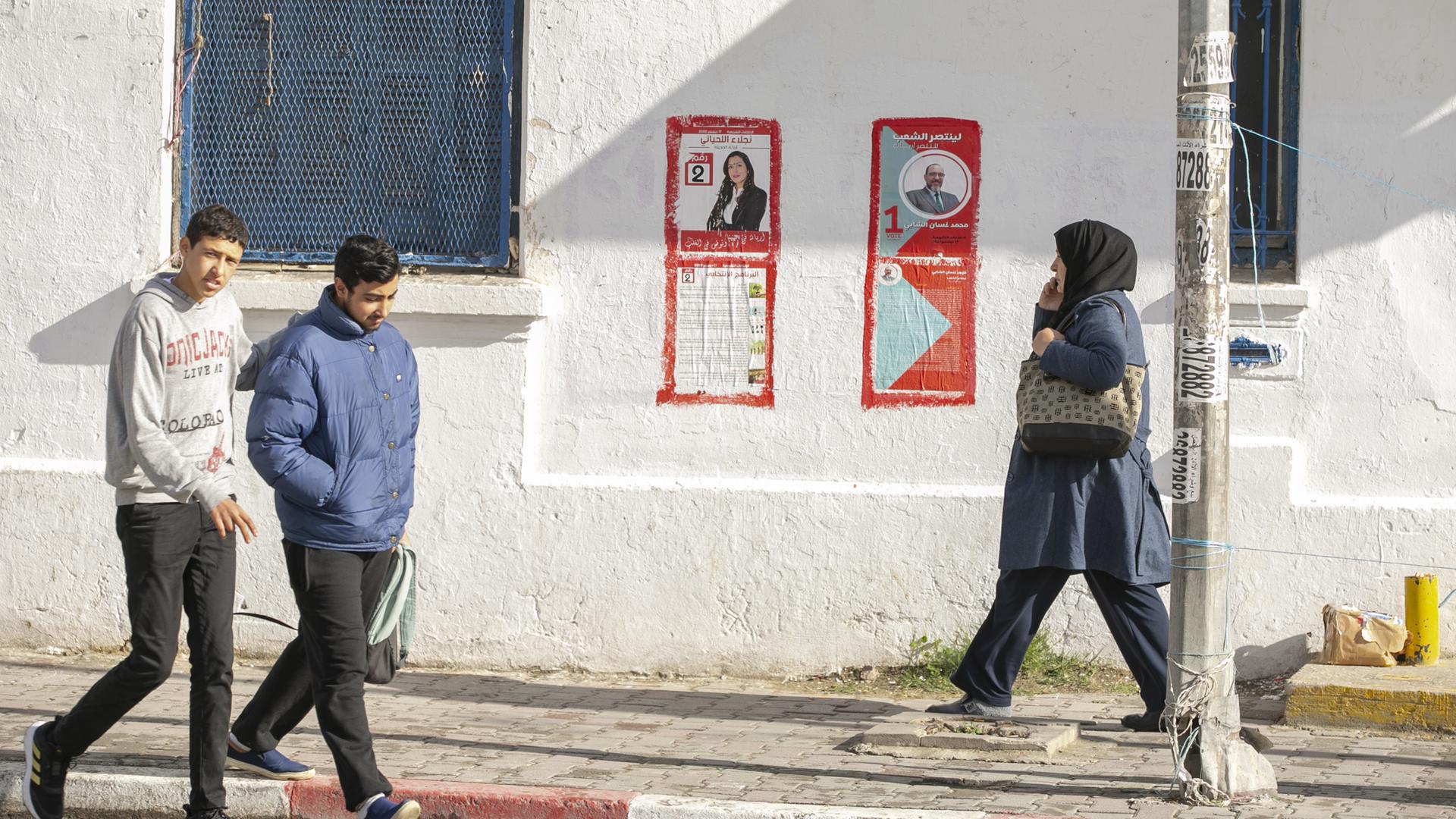 FUßgänger gehen an Wahlplakaten in Tunis vorbi. FUßgänger gehen an Wahlplakaten in Tunis vorbi.