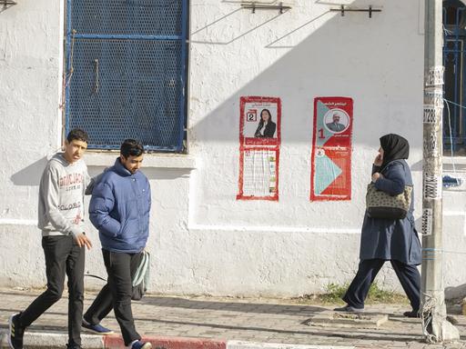 FUßgänger gehen an Wahlplakaten in Tunis vorbi. 