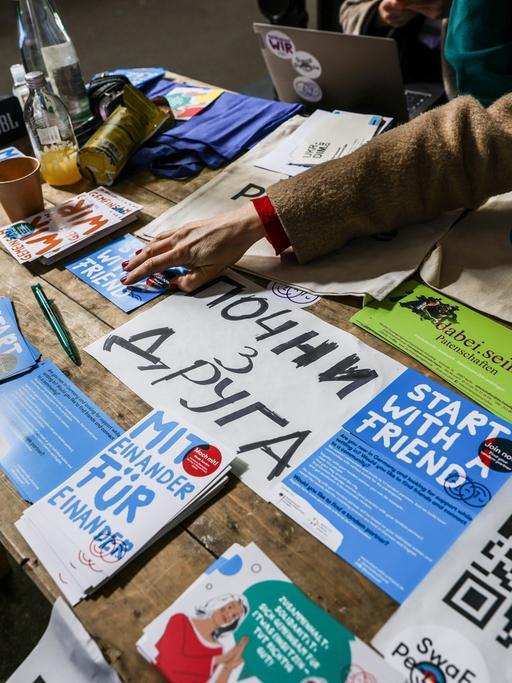 Flyer mit Informationsmaterial und Willkommensgrüßen auf Ukrainisch liegen auf einem Tisch aus.