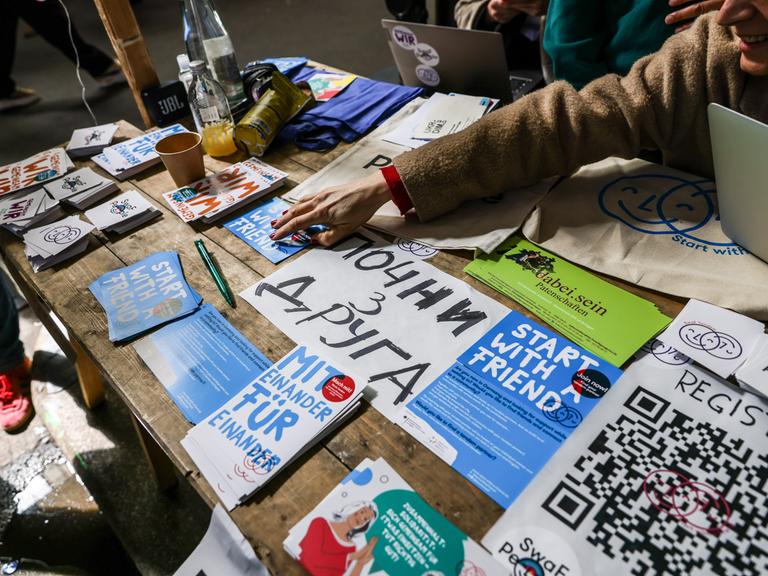 Flyer mit Informationsmaterial und Willkommensgrüßen auf Ukrainisch liegen auf einem Tisch aus.