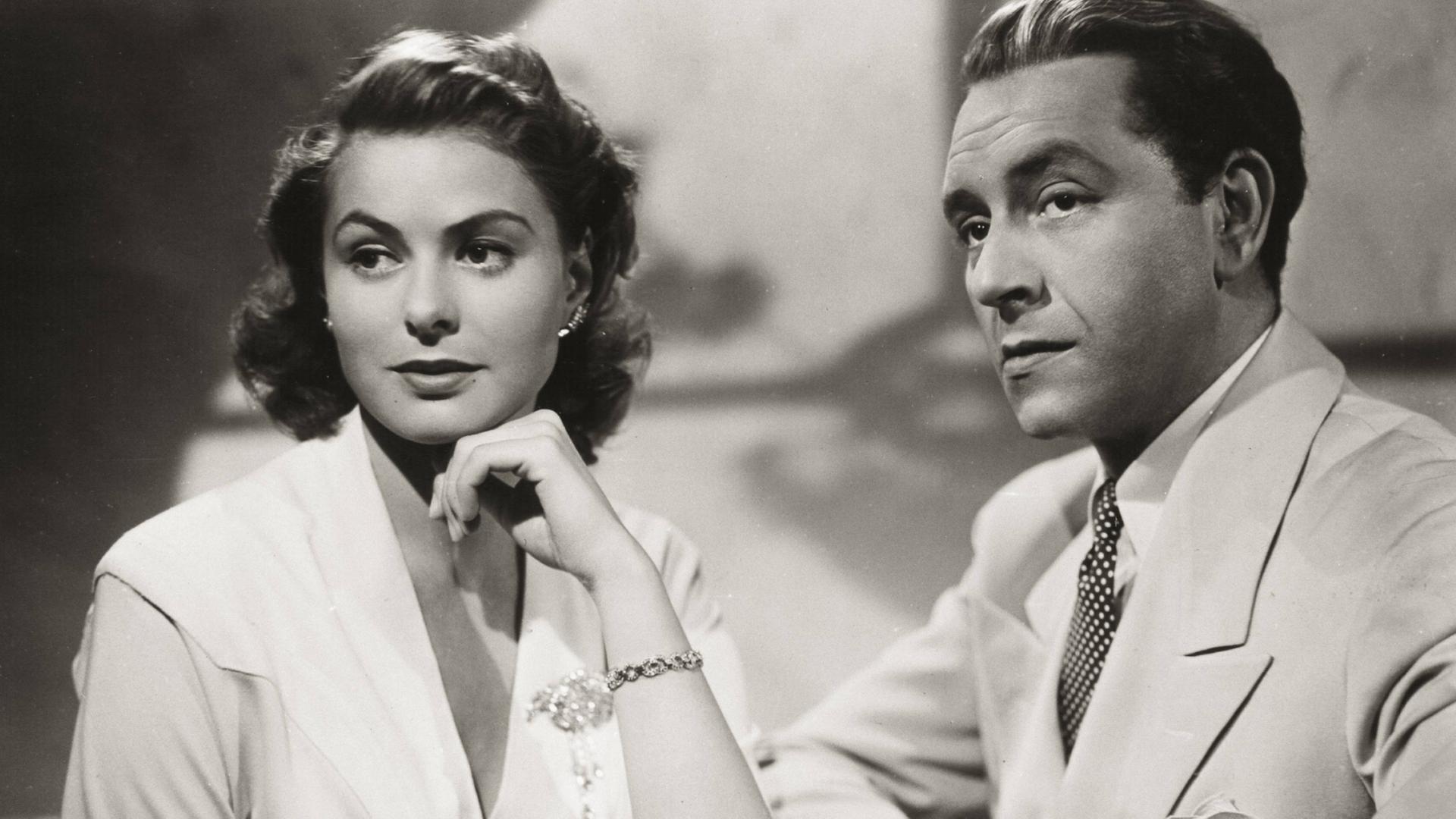 Historisches Schwarzweißfoto von Ingrid Bergman und Paul Henreid, die mit ernstem Blick nebeneinander sitzen. Historisches Schwarzweißfoto von Ingrid Bergman und Paul Henreid, die mit ernstem Blick nebeneinander sitzen.