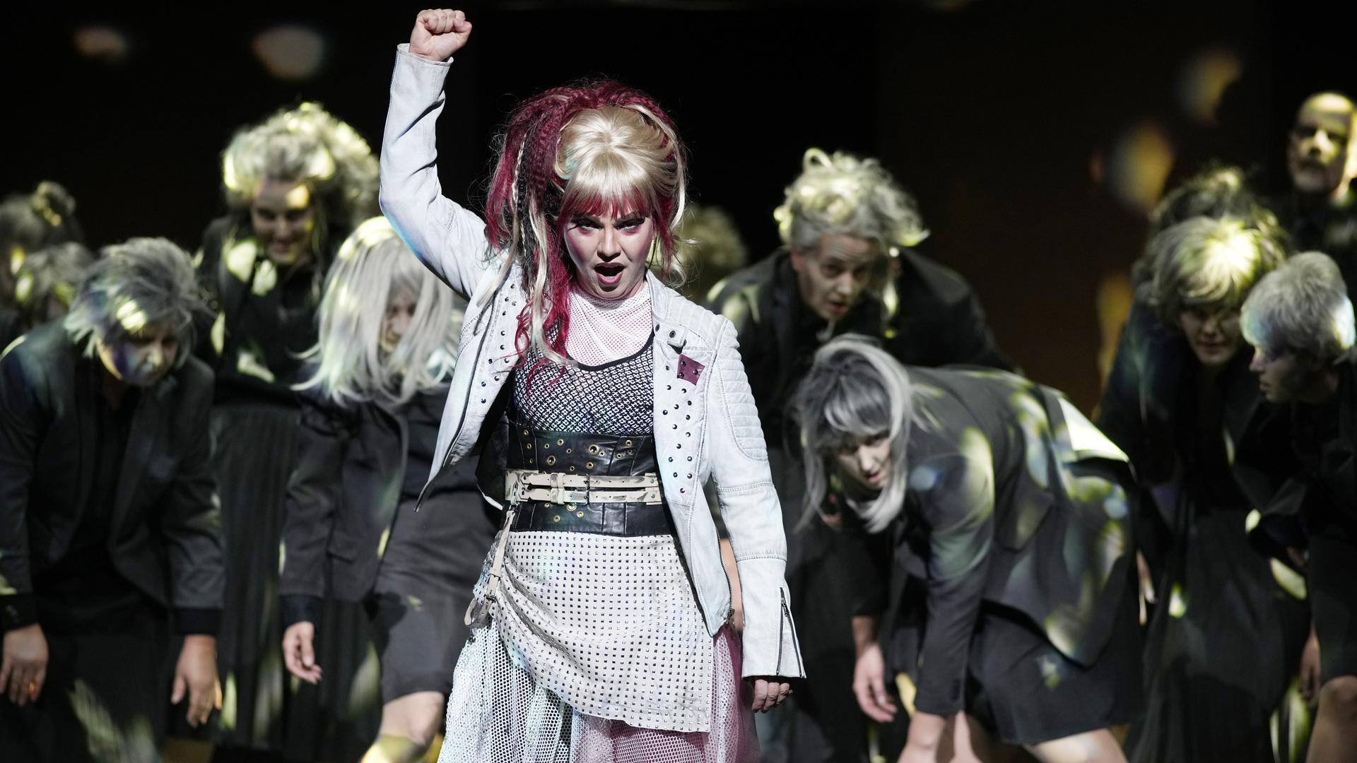 Eine Frau auf der Bühne reckt kämpferisch die Faust in die Höhe. Eine Frau auf der Bühne reckt kämpferisch die Faust in die Höhe.