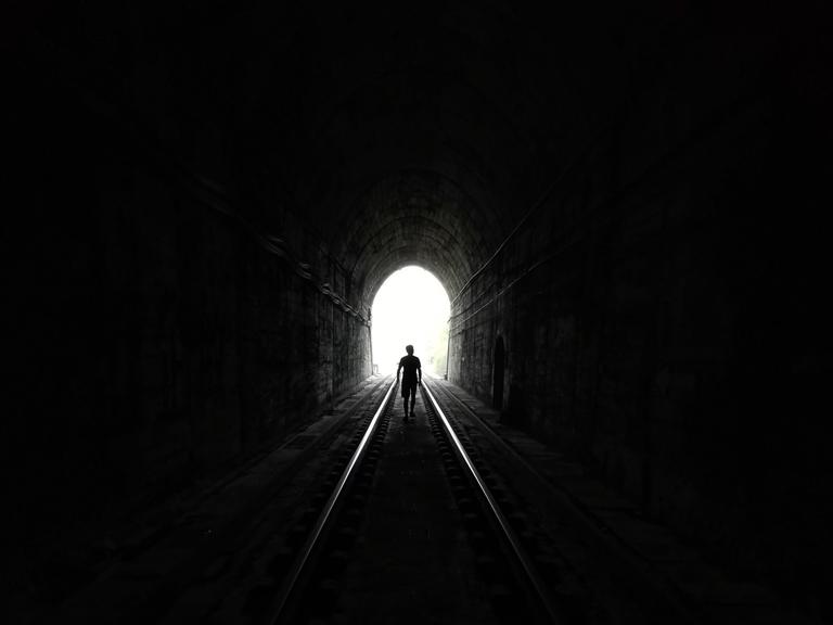 Eine Person läuft auf das Licht am Ende eines Tunnels zu.