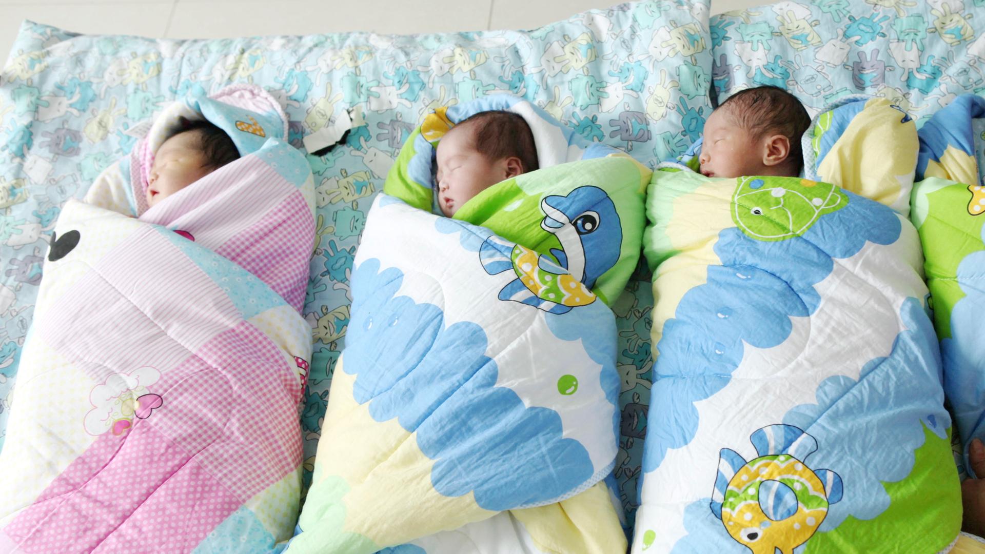 Frisch geborene Babies liegen in Decken gewickelt auf einem Tisch Frisch geborene Babies liegen in Decken gewickelt auf einem Tisch