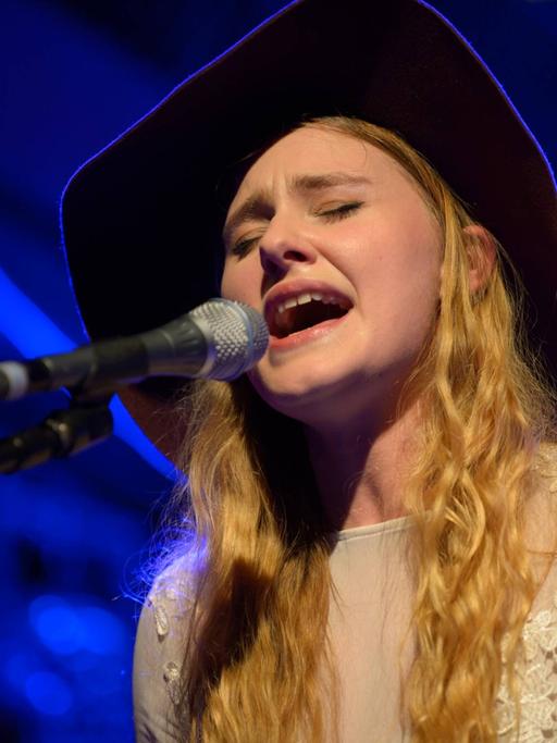 Die Sängerin Mia Diekow hat die Augen geschlossen und singt in in Mikrofon - sie trägt einen schwarzen Cowboy-Hut.