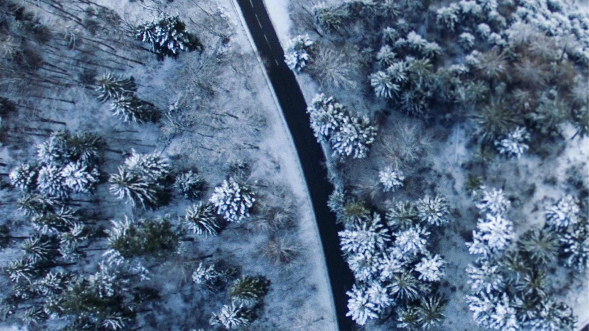 Eine sich schlängelnde Straße in verschneiter Waldlandschaft aus der Vogelperspektive. Eine sich schlängelnde Straße in verschneiter Waldlandschaft aus der Vogelperspektive.