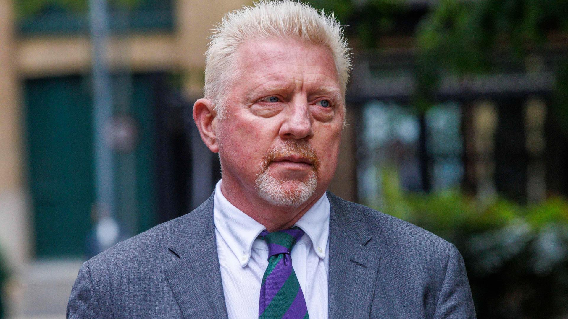 Ein Mann mit blonden Haaren trägt einen grauen Anzug und eine grün-violett gestreifte Krawatte. Ein Mann mit blonden Haaren trägt einen grauen Anzug und eine grün-violett gestreifte Krawatte.