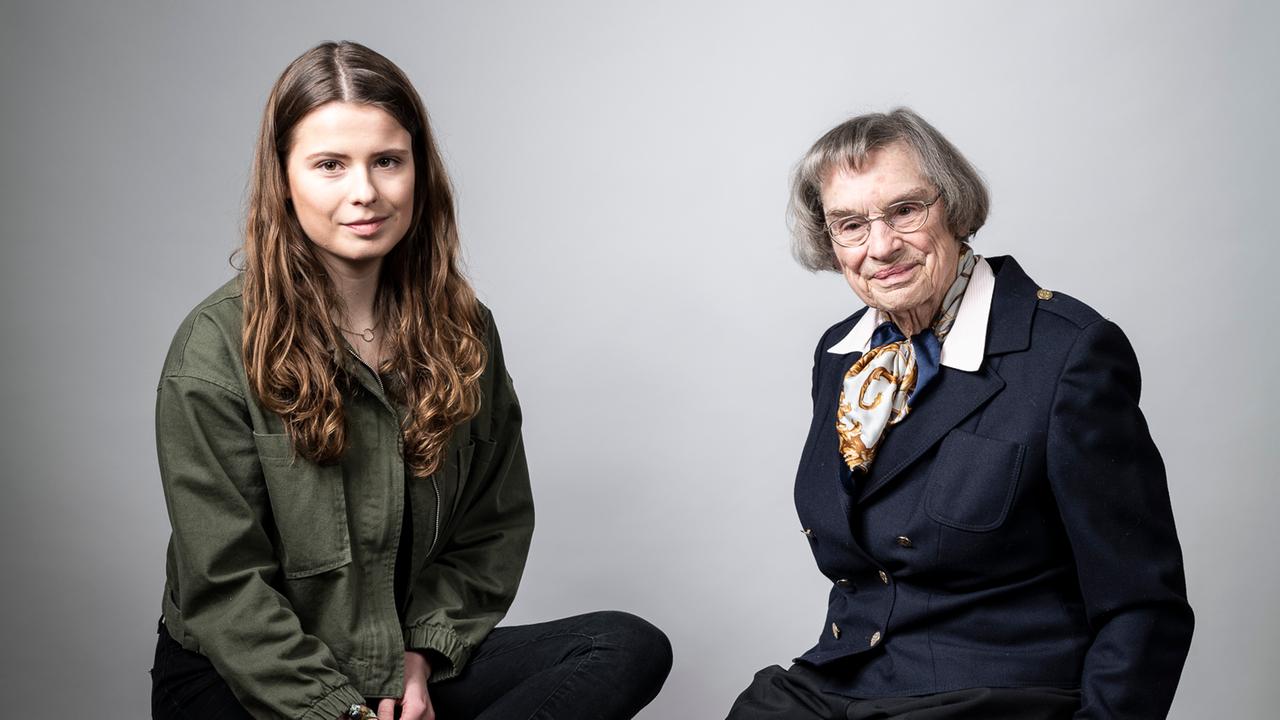 Das Bild zeigt die junge Klimaaktivistin Luisa Neubauer  mit langen braunen Haaren und ihre Großmutter Dagmar Reemtsma mit kurzer Pagenkopf-Frisur. Beide sitzen vor einem hellgrauen Hintergrund auf hohen Barhockern und schauen in die Kamera.
