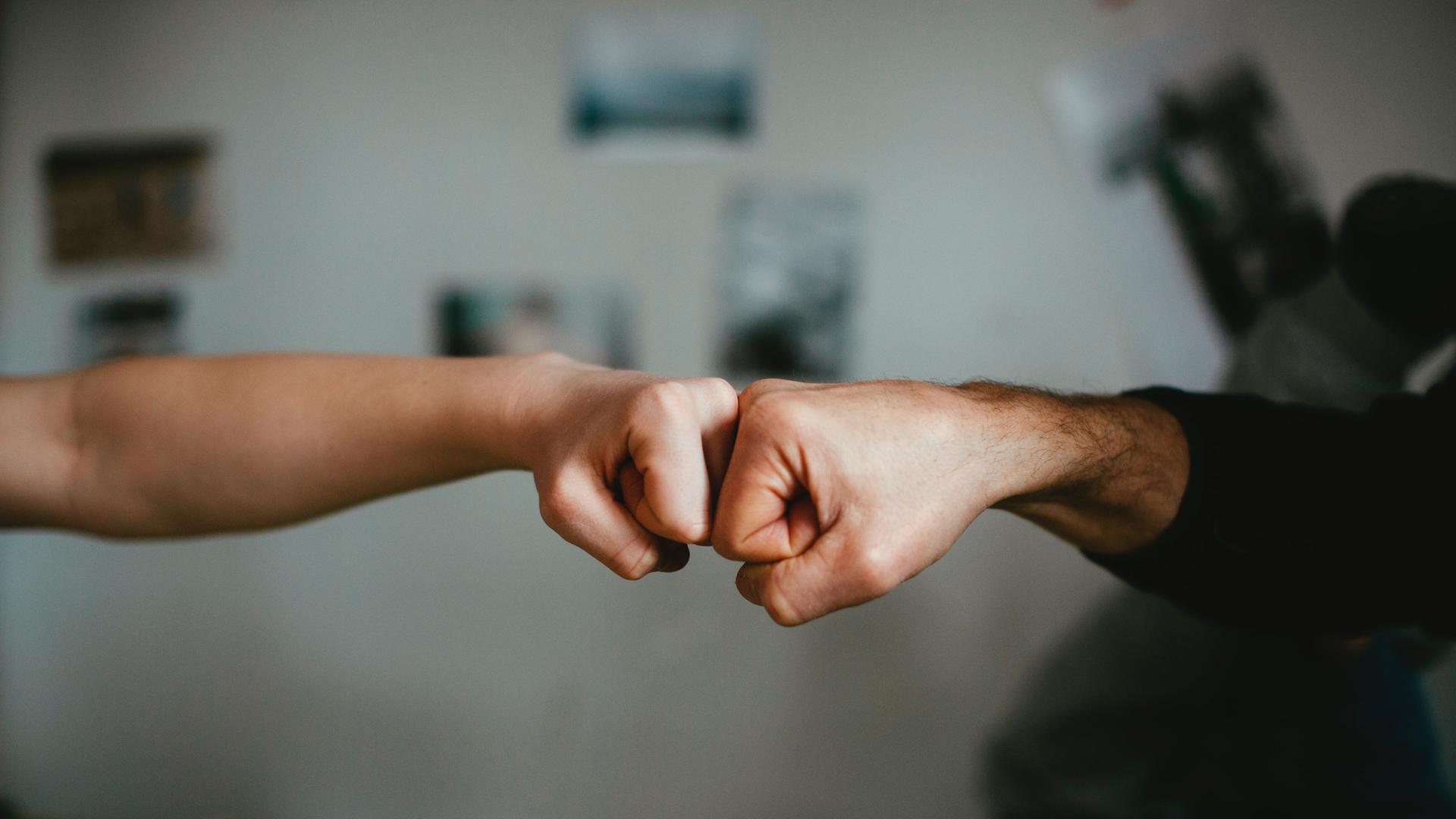 Zwei Personen begrüßen sich mit den Fäusten. Zwei Personen begrüßen sich mit den Fäusten.