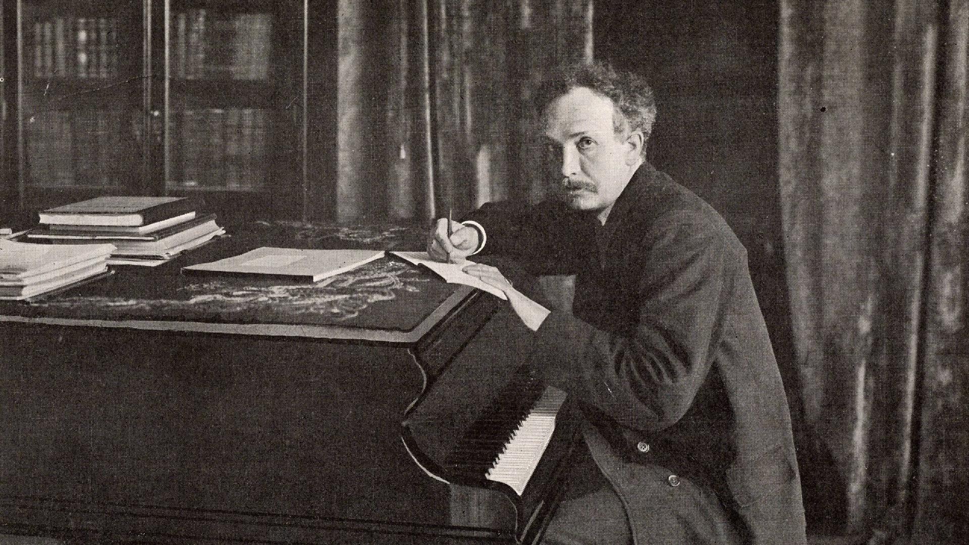 Ein Mann sitzt vor einem Klavier und schreibt Noten auf ein Blatt Papier. Es ist der Komponist Richard Strauss. Ein Mann sitzt vor einem Klavier und schreibt Noten auf ein Blatt Papier. Es ist der Komponist Richard Strauss.