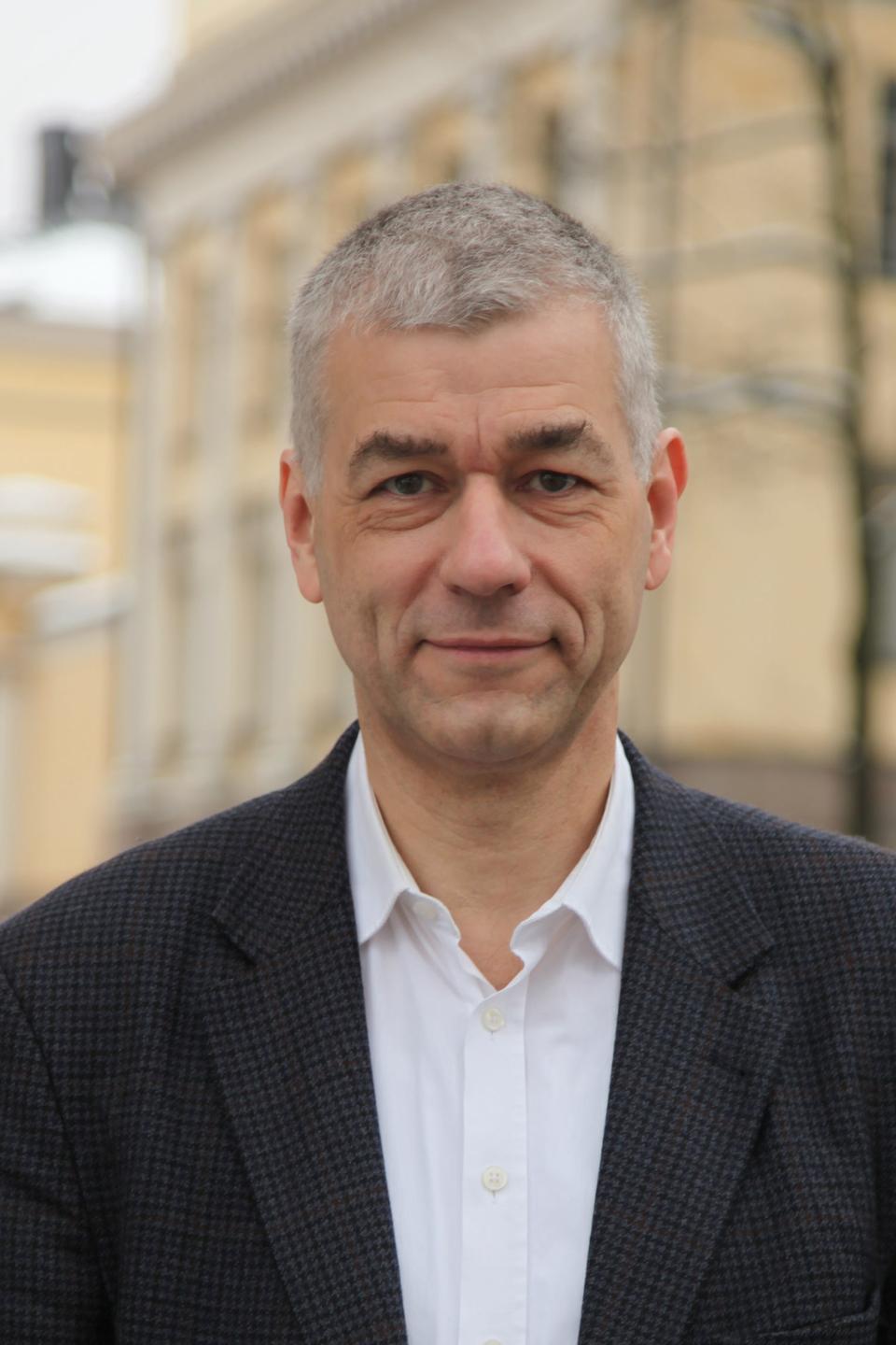 Thomas Bremer, mit kurzen grauen Haaren, im dunklen Sakko und weißen offenen Hemd, schaut entspannt in die Kamera. Thomas Bremer, mit kurzen grauen Haaren, im dunklen Sakko und weißen offenen Hemd, schaut entspannt in die Kamera.